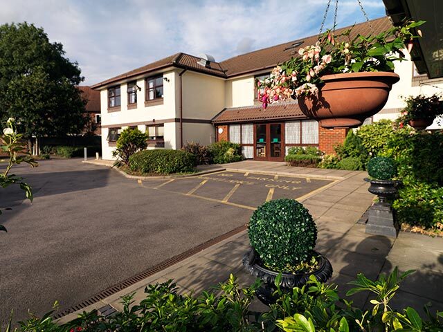 The welcoming entrance to Vicarage Farm Care Home, with hanging baskets in flower