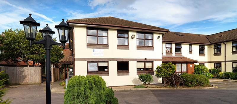 A carer with residents in the lounge at Vicarage Farm Care Home